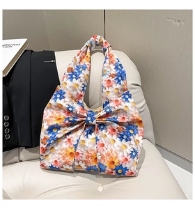 Detail of floral handbag with colorful daisy print and a large decorative bow