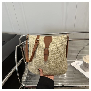 Detail of hand-held straw woven square bag with brown leather trim and zipper closure