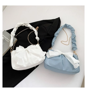Détail de sacs à bandoulière avec nœuds, poignées plissées et chaînes dorées