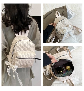Detail of cream straw mini backpack with lace pearl bow and interior storage space