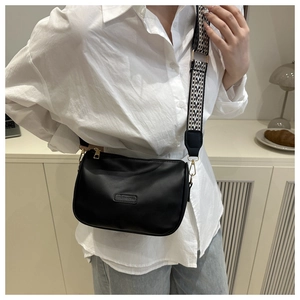Detail of black crossbody bag with wide geometric pattern strap and gold hardware