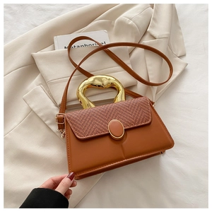 Detail of checkered woven flap bag with a unique gold-tone metal handle and leather finish
