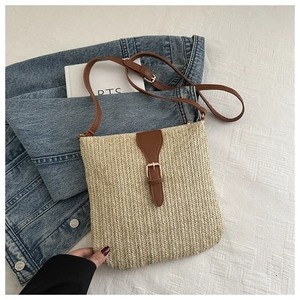 Detail of hand-woven straw crossbody bag with brown leather strap and metal buckle closure