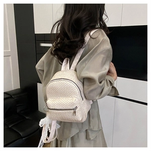 Detail of cream woven mini backpack featuring a pearl lace pendant and metallic zipper
