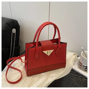 Detail of red paneled handbag featuring smooth and croc-embossed leather with metal lock