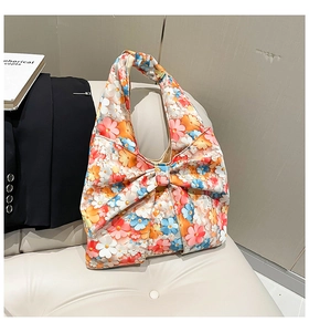 Detailed shot of floral print handbag with a large 3D bow and stylish ruffled handle