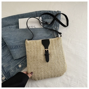 Detail of woven straw crossbody bag featuring black lychee leather trim and gold buckle