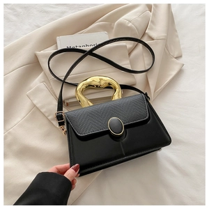 Detail of lizard-embossed leather black crossbody bag with gold metal handle and hardware