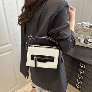 Borsa rettangolare a contrasto con finiture dorate indossata da una modella per il lavoro