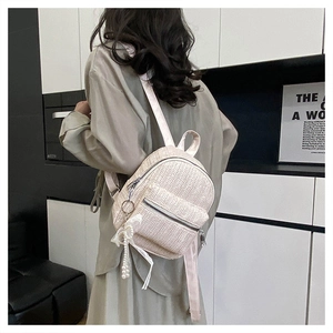 Detail of cream woven backpack with pearl beads and white satin ribbon bow charms