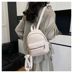 Detail of cream woven backpack with lace pearl charm and gold-tone zippers
