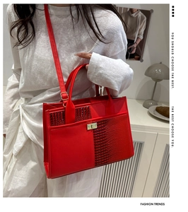 Detail of red crocodile texture tote bag with gold buckle on a model shoulder