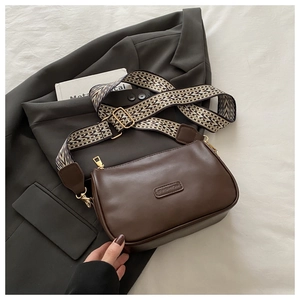 Close-up of brown faux leather crossbody bag with geometric jacquard wide shoulder strap