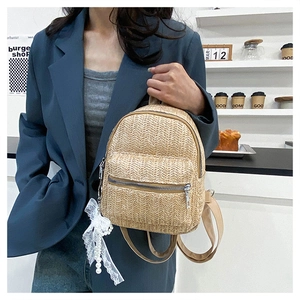 Close-up of beige woven mini backpack with lace pearl charm and leather straps