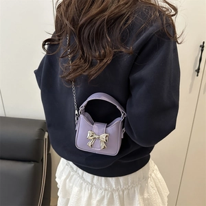 Purple mini crossbody bag with silver metal bow and chain strap on female model