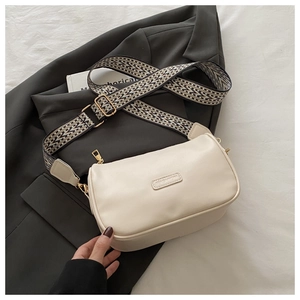 Detail of cream crossbody bag featuring fashion embossed texture and woven strap