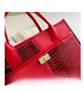 Close-up of red crocodile pattern patchwork handbag with golden turn-lock and metal hardware