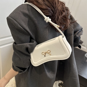 Chic white leather shoulder bag featuring a gold bow clasp and stylish knotted strap