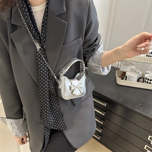 Mini silver metallic handbag with bow detail and chain strap worn by a fashion model