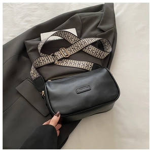 Close-up of black crossbody bag with fashion tag and colorful woven wide strap details