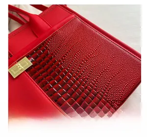 Close-up of red crocodile embossed leather tote with a gold twist-lock metal fastener