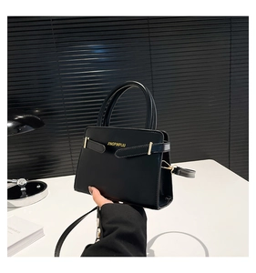 Détail du sac à main en cuir noir avec logo JINGPINPIJU doré et boucles décoratives