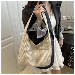 Detail of beige woven tote bag showing honeycomb texture and magnetic metal clasp