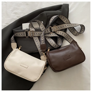 Detail view of stylish cross-body bags in cream and brown with geometric patterned wide straps