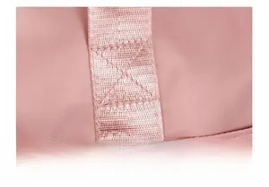 Macro shot of X-shaped reinforced stitching on pink travel bag for enhanced durability