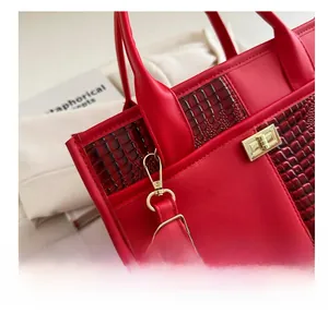 Close-up of red crocodile pattern texture and premium gold metal hardware on handbag