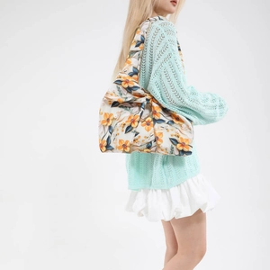 Floral print tote bag with oversized bow detail carried by model in a clean studio setting