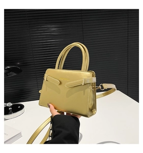 Détail d'un sac à main doré métallisé avec texture gaufrée et bandoulière amovible