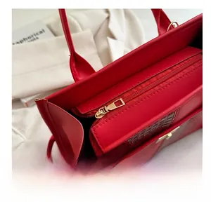 Close-up of smooth golden zipper and red crocodile texture on a stylish tote handbag