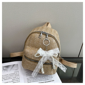 Detail of straw mini backpack featuring lace bow, pearl accents and leather straps