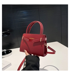 Détail du sac à main en cuir rouge foncé avec boucles dorées et texture mate raffinée