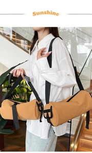 Detail of two sizes khaki PU cylindrical Boston bags with black adjustable nylon straps