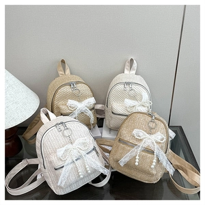 Detail of straw woven backpack with lace bow, pearl tassels and metal ring zipper