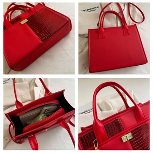 Detail view of red faux leather tote bag with crocodile texture and gold-tone twist lock