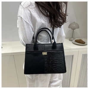 Detail of elegant black crocodile pattern tote with metallic gold buckle and dual handles