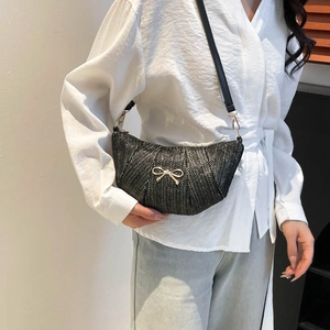 Chic black woven crescent shoulder bag featuring a stylish gold bow metal accent and slim strap