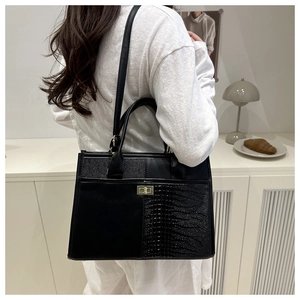 Crocodile pattern patchwork handbag with gold metal lock shown on a model