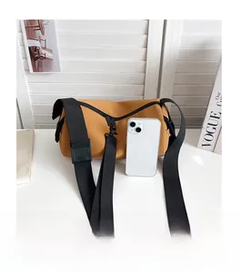 Nylon cylinder bag with black fabric strap shown next to an iPhone for size scale