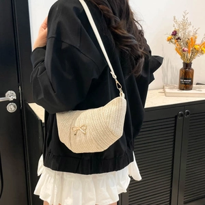 Beige woven straw crossbody bag with gold bow accent and adjustable white strap