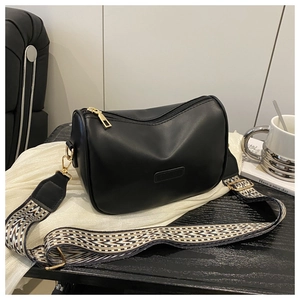 Detail of black crossbody bag with decorative geometric fabric strap and gold hardware