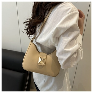 Détail de sac hobo beige avec de grands clous carrés dorés sur une surface en similicuir