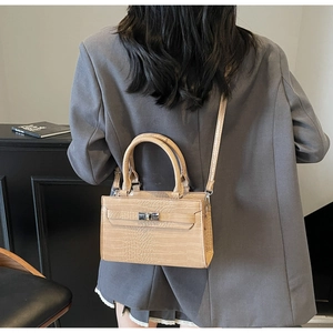 Detail shot of a khaki crocodile pattern handbag being worn in a stylish office setting