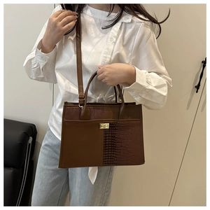 Close-up of brown crocodile texture stitching and gold metal twist lock on tote bag