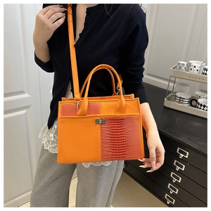 Detail of orange tote bag showing contrast between smooth leather and crocodile texture