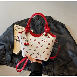 Détail du sac à bandoulière en cuir blanc avec imprimés cerise et bords ondulés