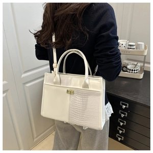 Detail showing white crocodile pattern patchwork and golden metal twist lock on tote bag